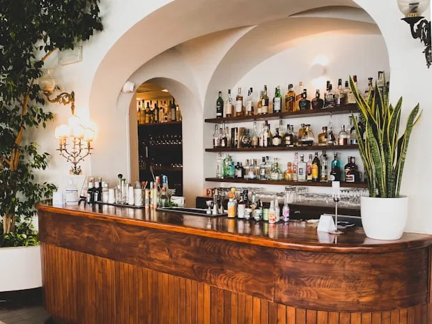 Barra de bar de madera con estantería de botellas detrás