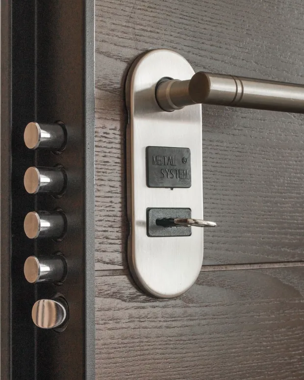 Canto de una puerta acorazada abierta: cinco bulones de acero y la llave puesta en la cerradura