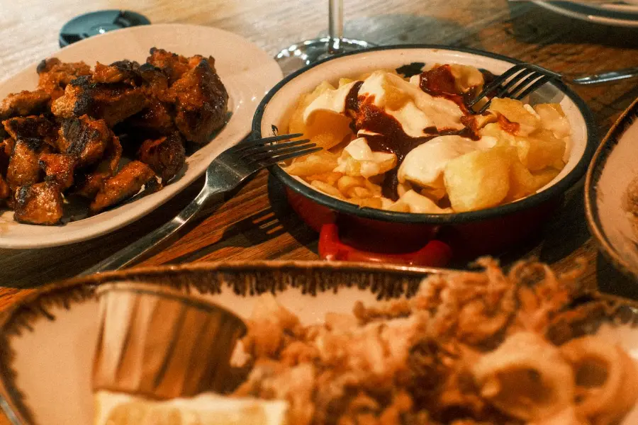 Mesa con raciones para compartir y una copa de vino tinto