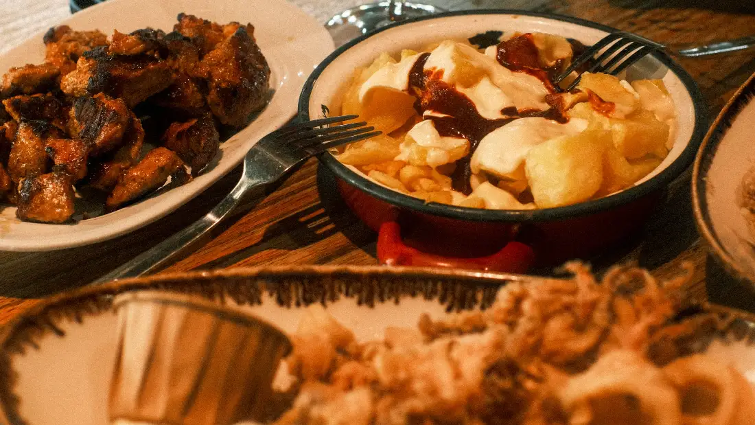 Mesa con raciones para compartir y una copa de vino tinto