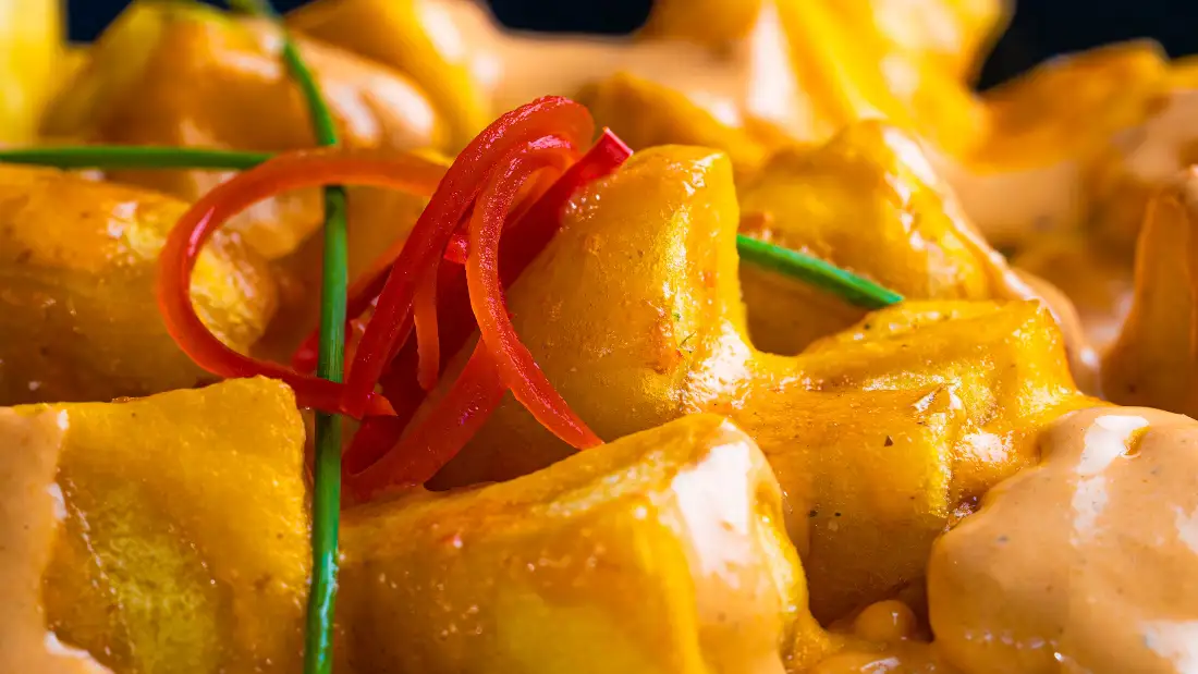 Primer plano de unas patatas bravas con su salsa