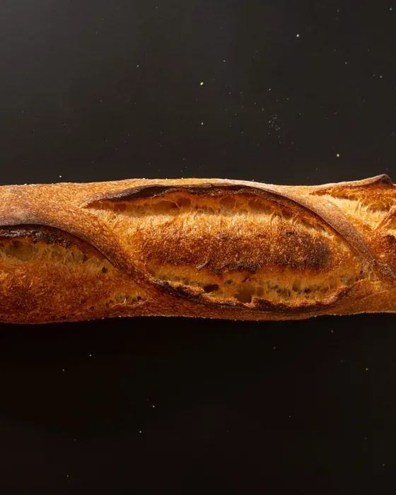 Barra de pan de corteza dorada sobre fondo oscuro